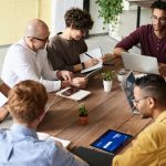 Eine Gruppe von Experten, die in einer modernen Büroumgebung eine Besprechung abhält, um notwendige Aktivitäten abzustimmen