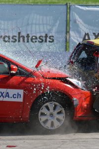 Red and yellow cars shown in a head-on collision during a crash test for safety evaluation.